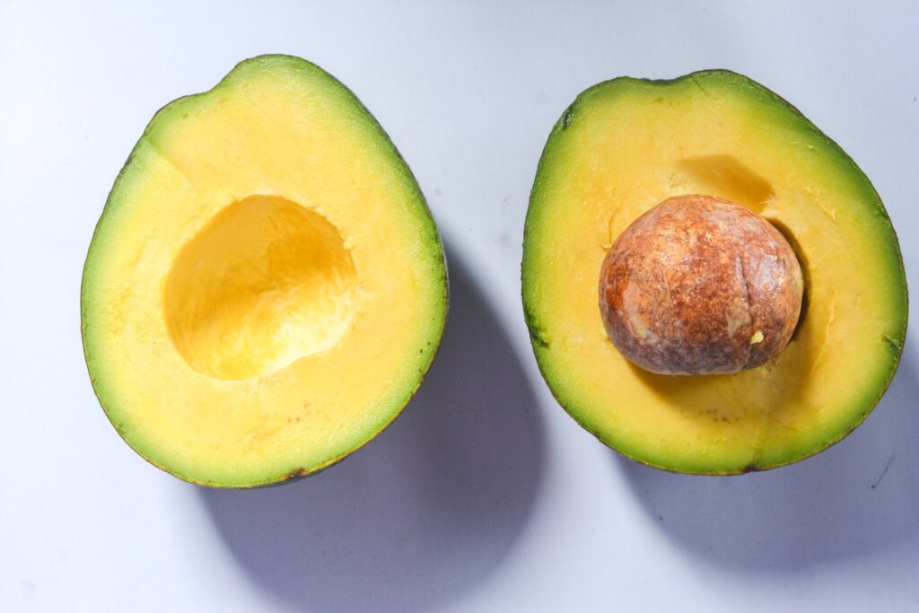 Fresh and ripe avocado fruit cut open on isolated white background